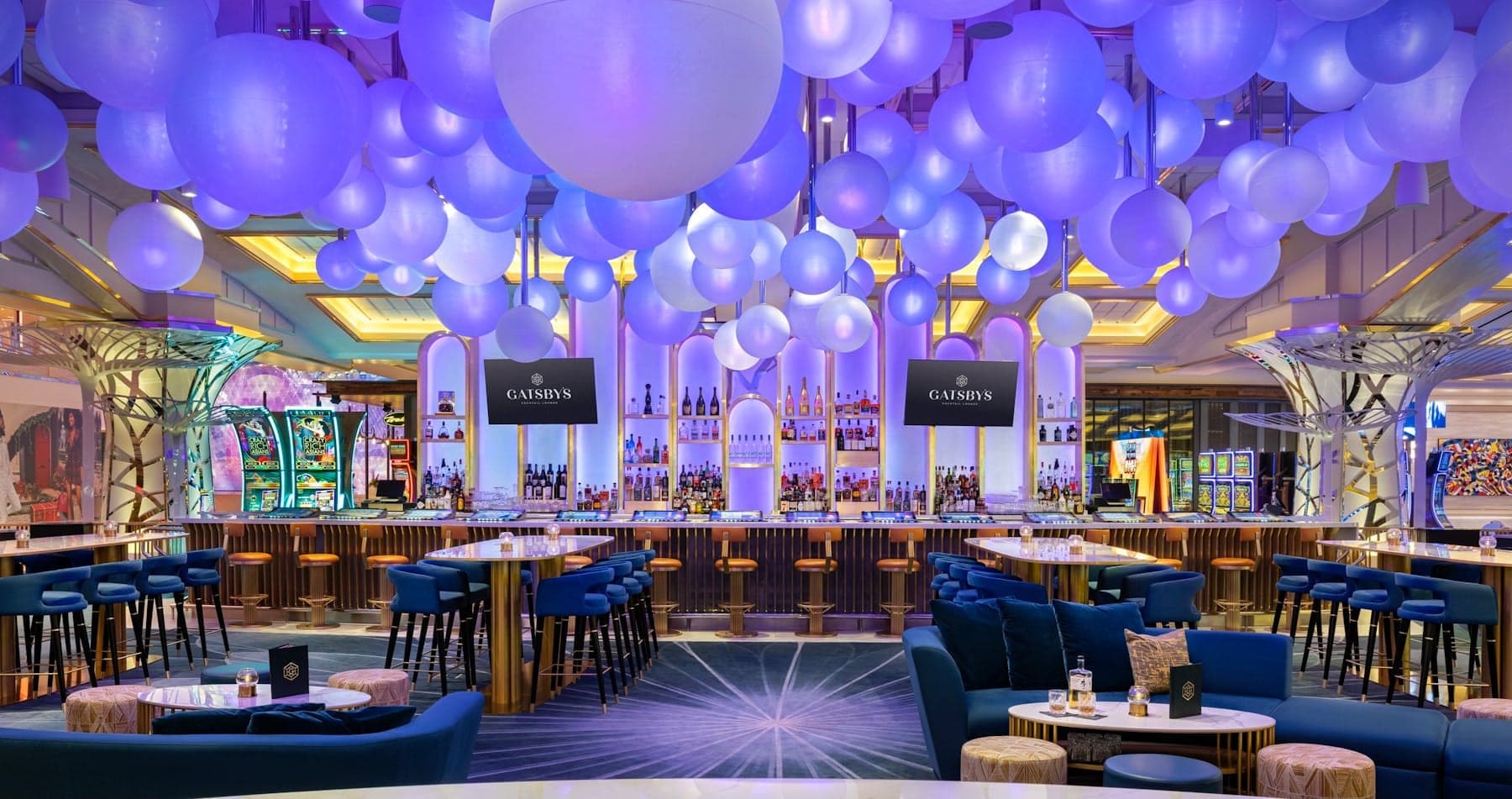 Gatsby’s bar with gold-front counter, bottle shelves, and lounge seating